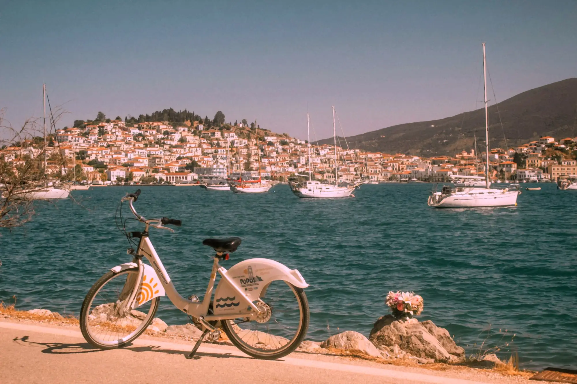 A bicycle parked on the waterfront at Galatas, with Poros town and yachts at anchor across the channel